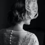 Back of a woman with a fascinator in an embroidered dress.